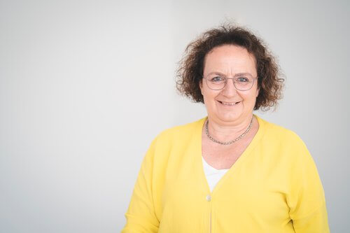 Barbara Kl&auml;sle mit lockigem, braunem Haar tr&auml;gt gelben Cardigan und wei&szlig;e Bluse.